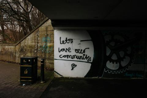 Untidy subway and rubbish bin with graffiti: Let's Love Our Community